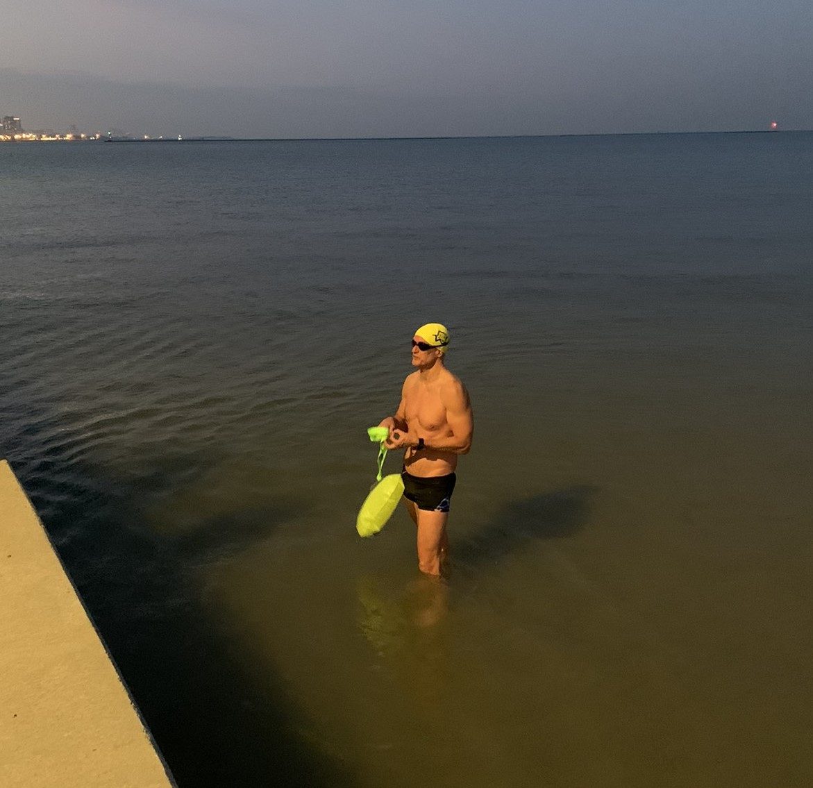 Max Munson in open water at dawn with a swim buoy