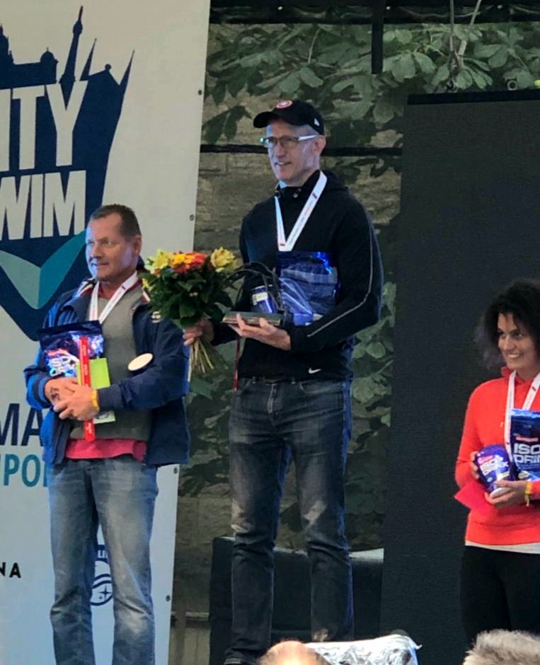 Max Munson on the podium with a trophy and medal at an ice swimming championship